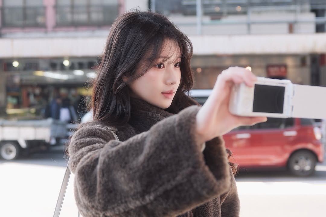 Photo by 이로아 on February 11, 2026. May be an image of one or more people, hair, phone, duffle coat, goosedown coat, parka, camera and text.