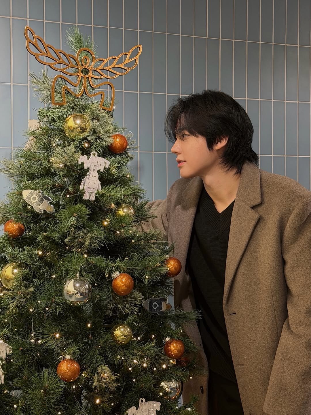 Photo by 유도열 on December 24, 2025. May be an image of one or more people, hair, christmas tree, duffle coat, tinsel and text.