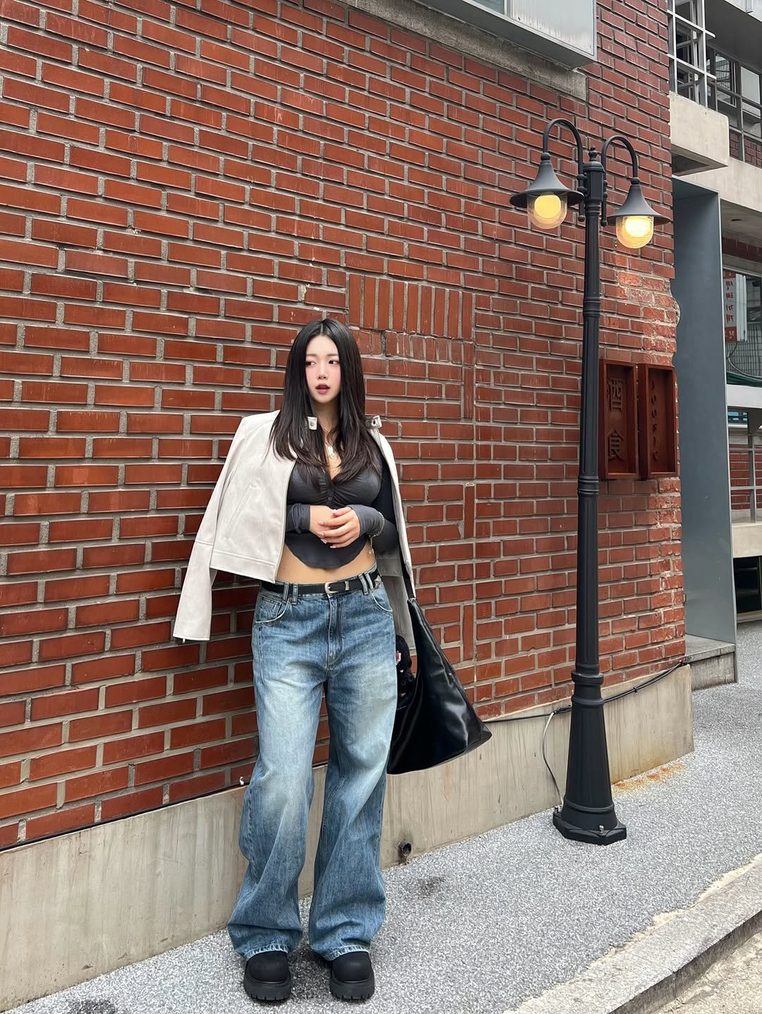 Photo shared by 지오 on September 12, 2025 tagging @musinsa.official, and @musinsa_standard. May be an image of 1 person, outerwear, brick wall, lamppost and text.