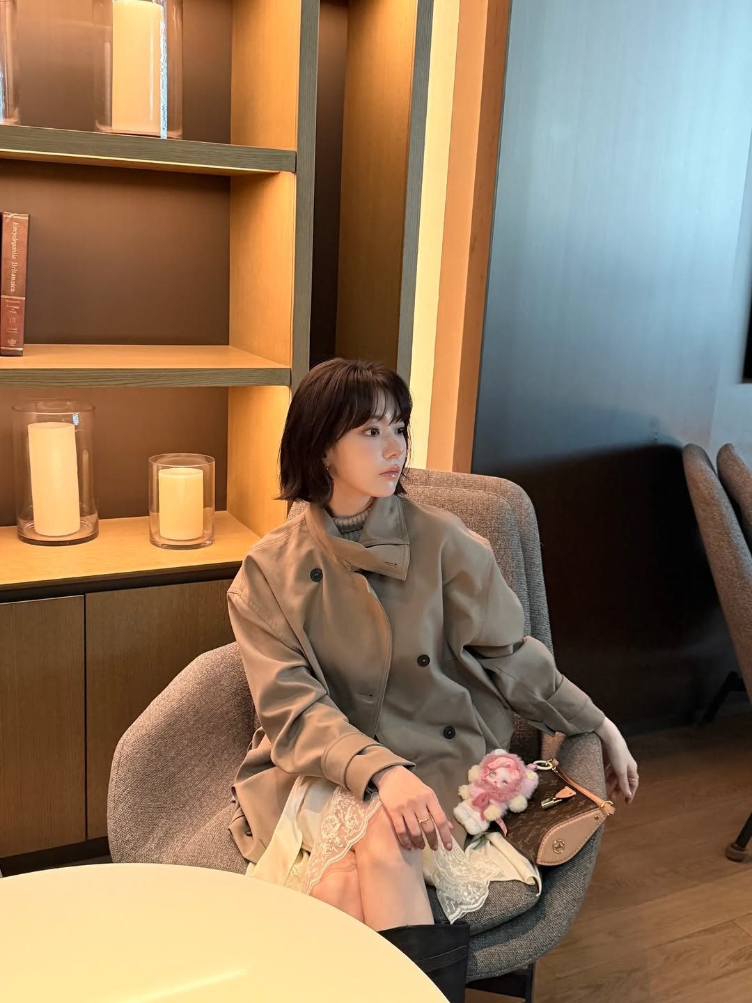 Photo by Sakura Miyawaki on March 11, 2026. May be an image of duffle coat, overcoat, blazer, armchair, candle and text.
