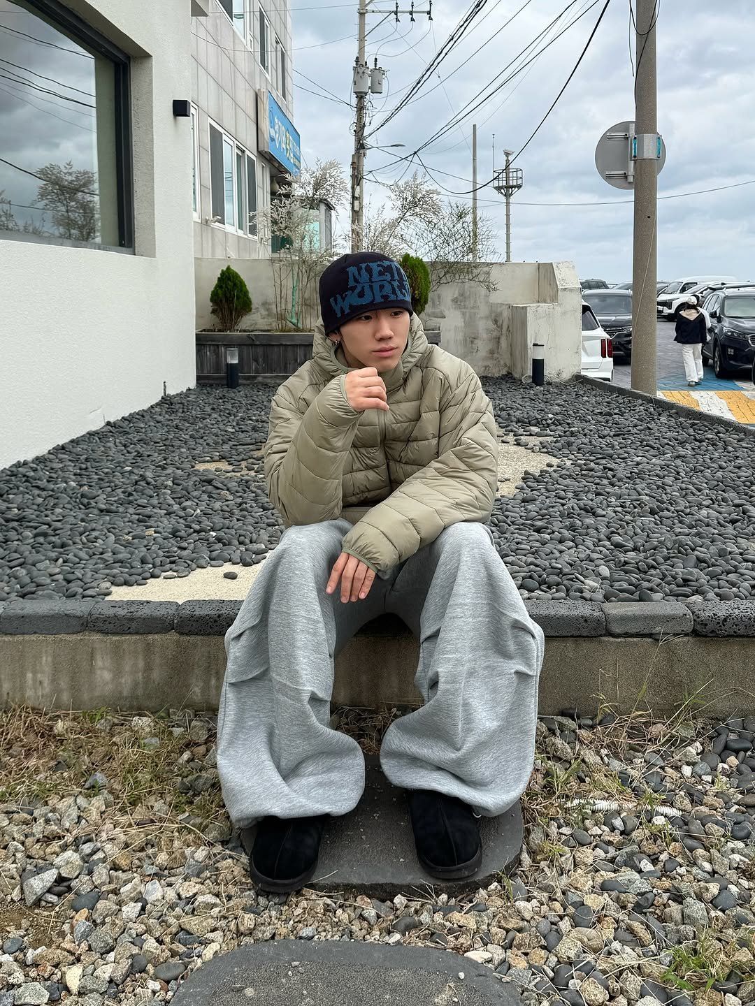 Photo by 김용빈 / 유포어 on October 22, 2025. May be an image of duffle coat, beret, parka, sweatpants, face mask, curb and text.
