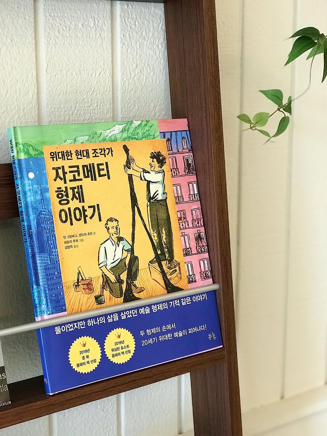 Photo by 봄나무 출판사 on September 03, 2025. May be an image of ‎towel rack, wind chime, step stool, book, ladder, poster, rack, shelf and ‎text that says '‎위대한 위대한현대조각가 현대 조각가 자코메티 형제 이야기 만그로없그. 냉든만조린 적모. 크인을 셀드라후 专料 ללבג 견업특놀리 둘이었지만 하나의 하나의삶 삶을 살았던 예술 형제의 기적 같은 이야가 두형제의손에서 두 두형제의 손에서 201일년 20세기 위대한 예술이 피어나다! 휠싱던 퀴심런포스캔 스콘 올아솥다. 선점 as 2018년 ه 충석 음색의해선점 선점 음혜의 la OD‎'‎‎.