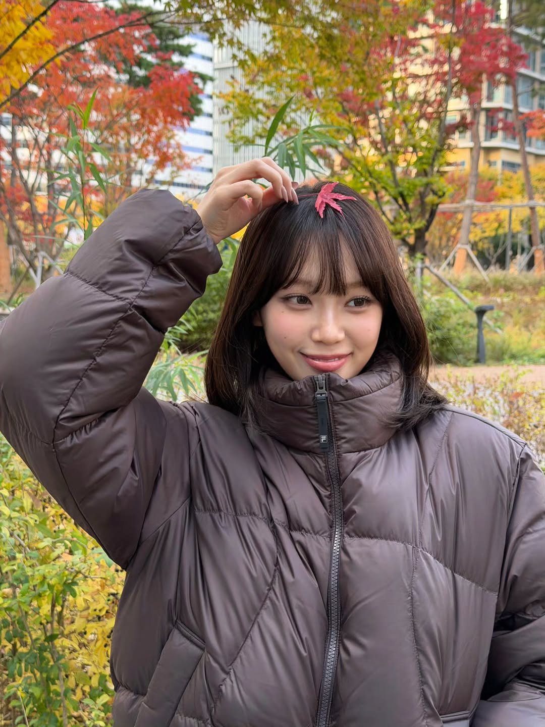 Photo shared by 김채원 (CHAEWON) on November 16, 2025 tagging @fila_korea. May be an image of one or more people, hair, duffle coat, goosedown coat, parka, outdoors and text.