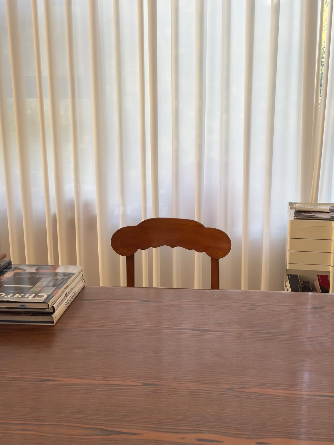 Photo by COLLECTION OF on September 21, 2025. May be an image of table, woodwork, curtains, dining table, kitchen table, indoors and text.