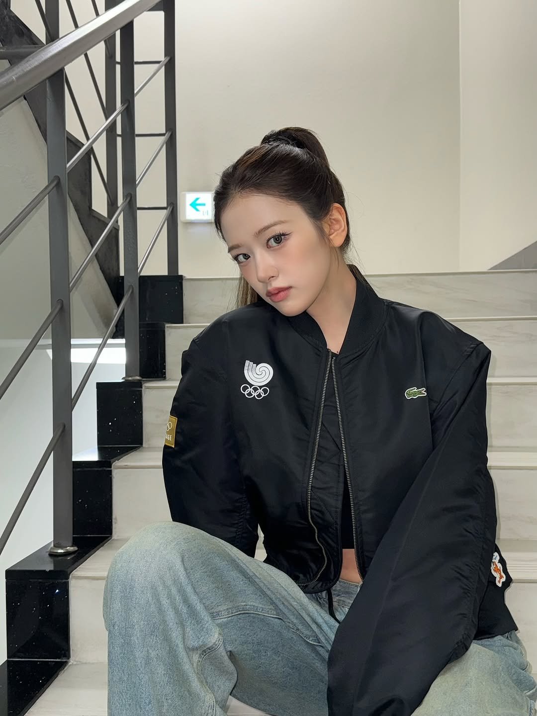 Photo shared by 안유진 AN YUJIN on September 04, 2025 tagging @lacoste, @olympics, and @olympic. May be an image of 1 person, flight jacket, top, parka, coat and text.