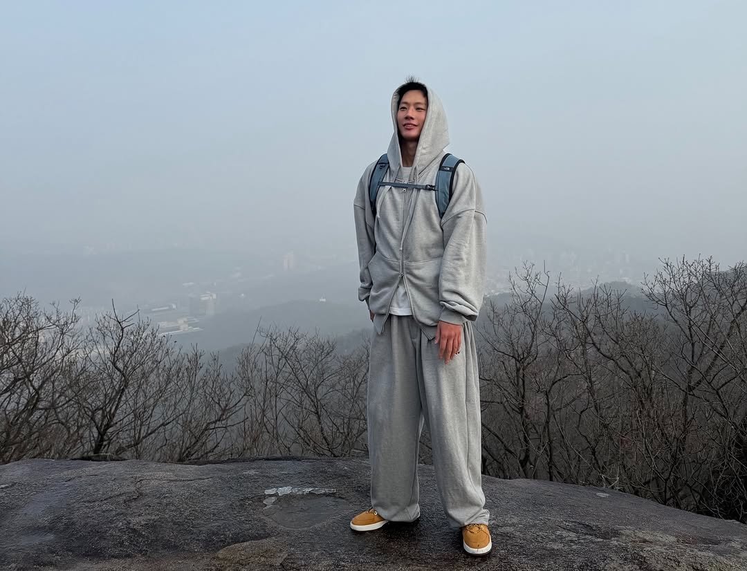 Photo shared by JIKWON on March 22, 2026 tagging @champ__official_. May be an image of standing, sweatsuit, sweatpants, park and text.