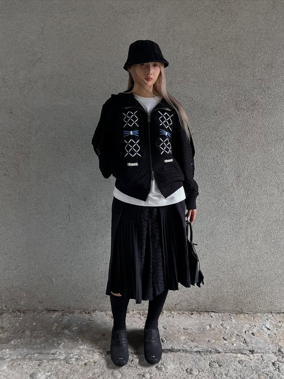 Photo by ADERERROR SPACE on September 24, 2025. May be an image of 1 person, vest, bowler hat, kilt, miniskirt, outerwear and text.