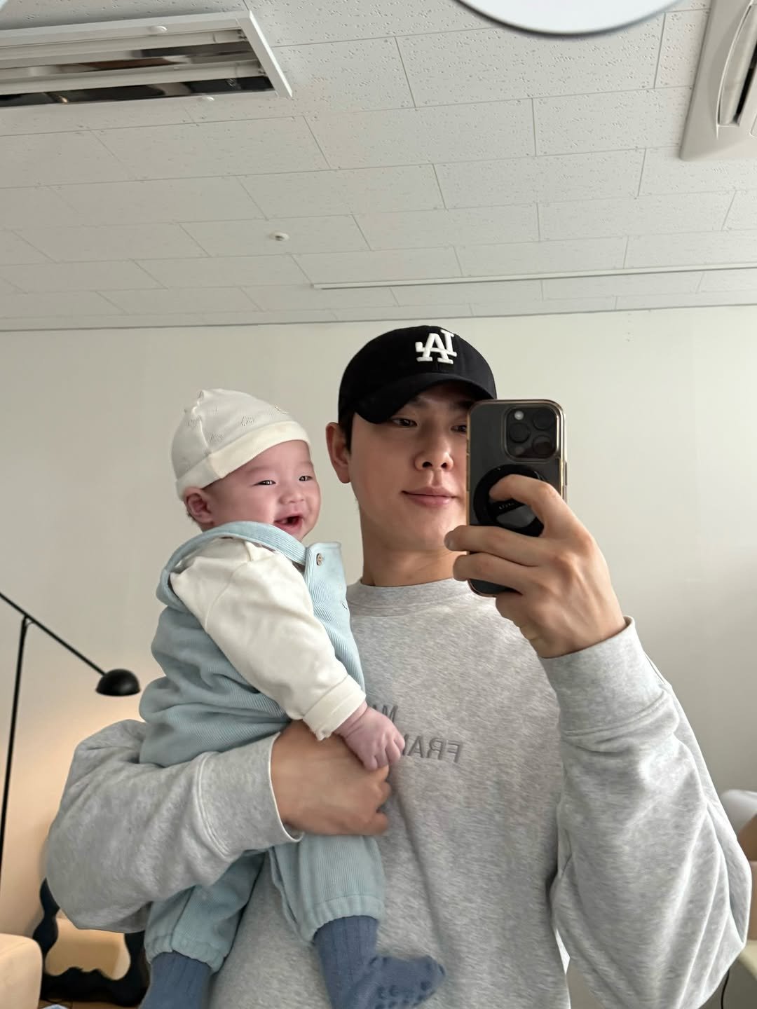 Photo shared by 박현호 on November 22, 2025 tagging @aiden_papa_. May be a selfie of baby, hat, sling, sweatpants and text.