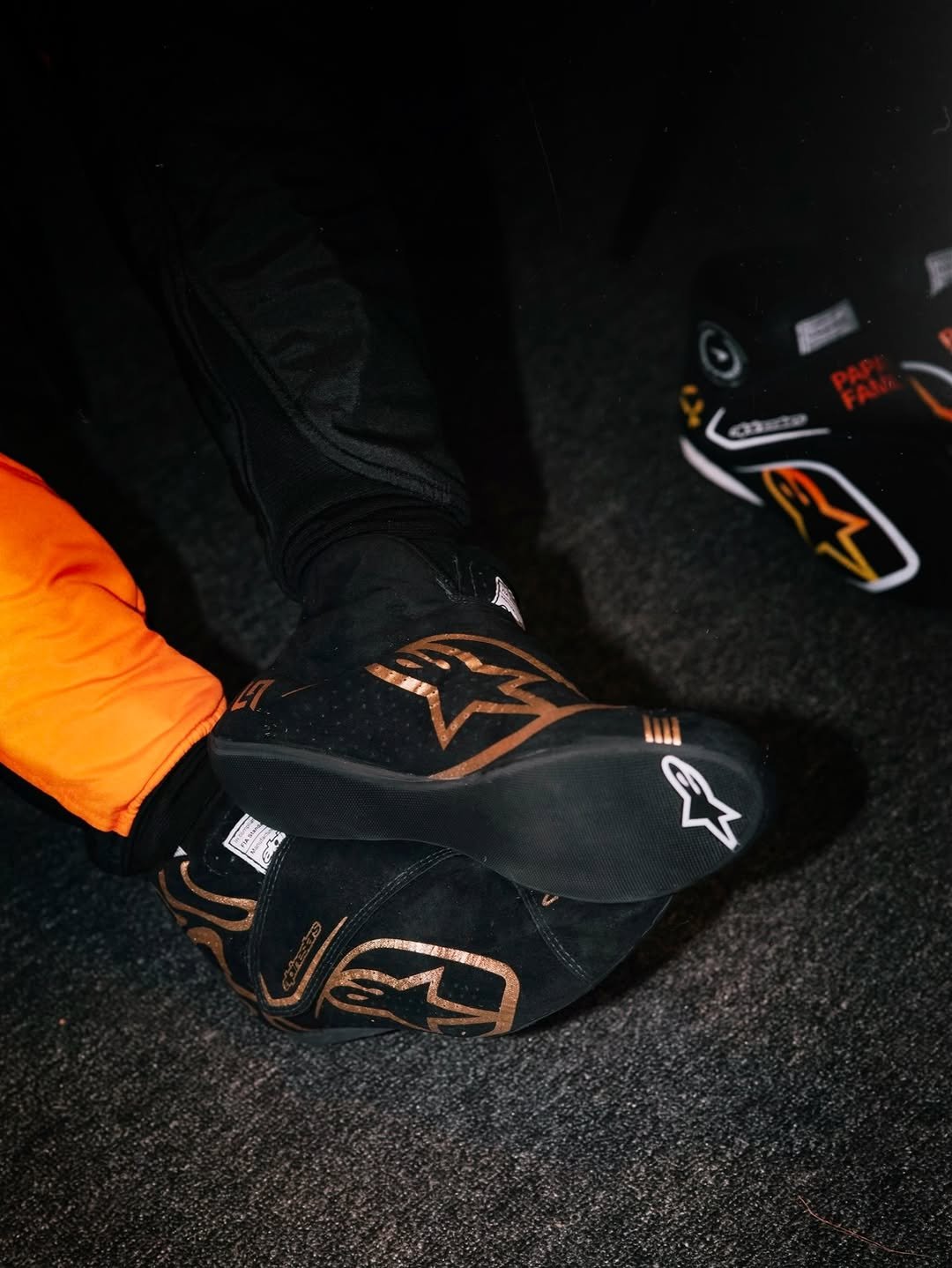 Photo shared by Alpinestars on December 14, 2025 tagging @mclaren, and @lando. May be an image of racing vehicles, face mask, toecap shoes, helmet and text.