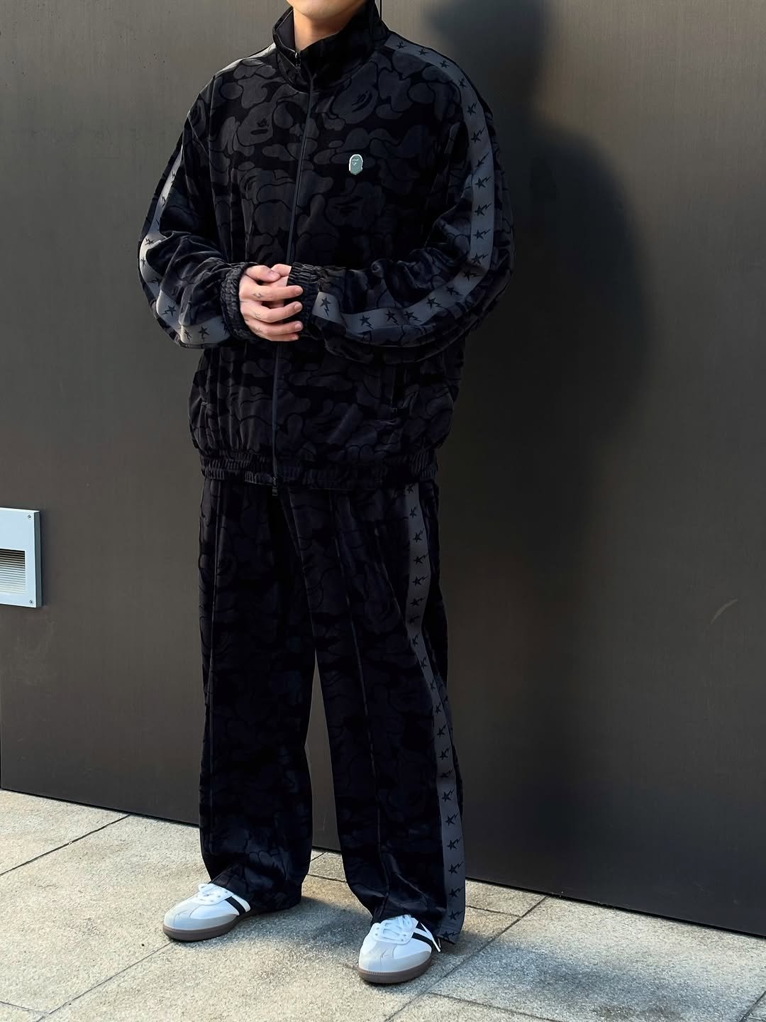 Photo shared by BAPE SEOUL on November 17, 2025 tagging @bapestorekorea, and @bape_seoul. May be an image of sweatpants, sweatsuit, brick wall and text.