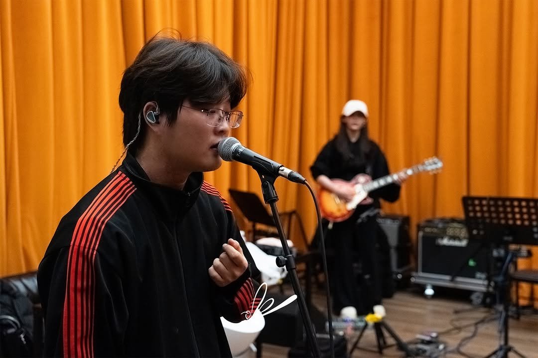 Photo shared by 메타코미디 on December 25, 2025 tagging @cjaewoo_97, @beautifulnerd__official, and @reddragonfly_official. May be an image of guitar, microphone, concert and text.