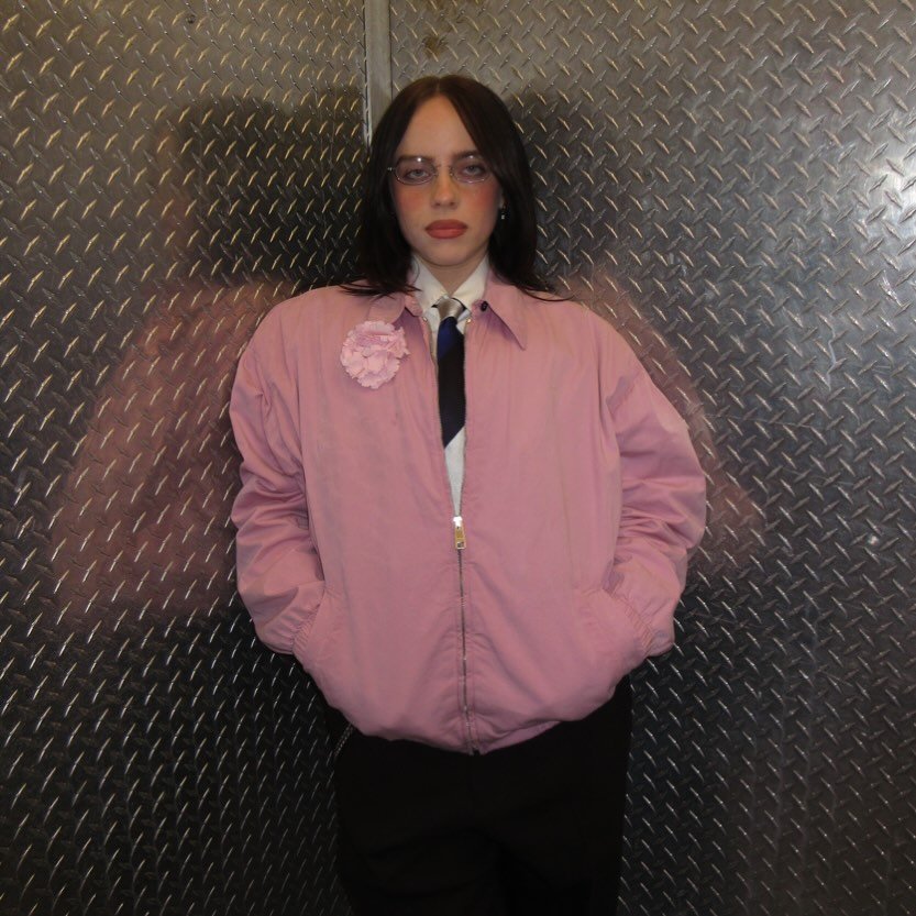 Photo by BILLIE EILISH on February 17, 2026. May be an image of suit, bolo tie, necklace, turtleneck, flight jacket, coat and text.