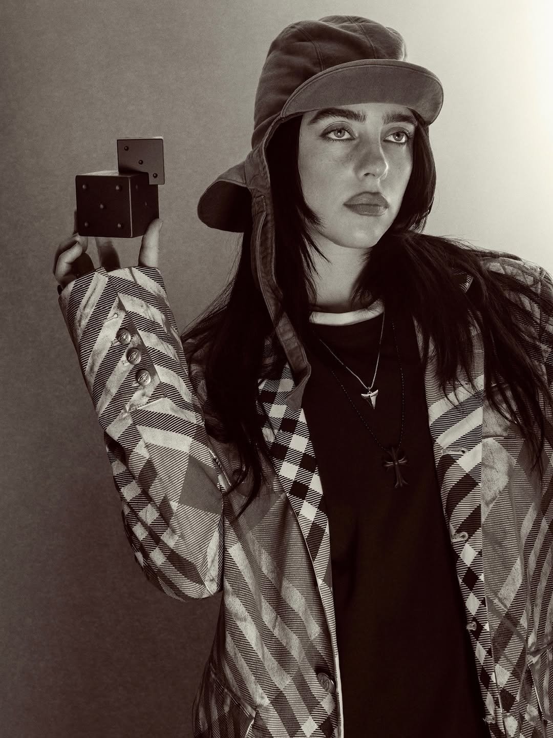 Photo shared by BILLIE EILISH on February 22, 2026 tagging @ultabeauty, @_glen_luchford, and @billieeilishfragrances. May be a black-and-white image of hat, beret, camera, bolo tie, outerwear, bandanna, headscarf, portable cassette player, bowler hat and text.