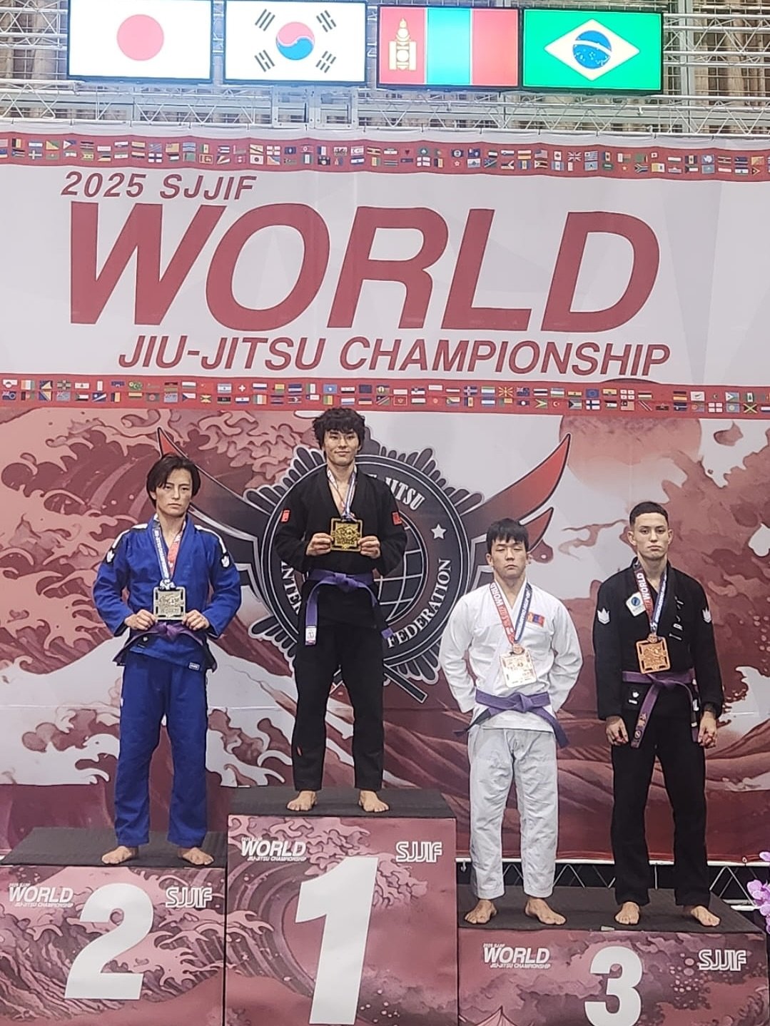 Photo by 주짓수매거진 on September 21, 2025. May be an image of ‎4 people, belt and ‎text that says '‎II Hh H H 2025 SJJIF WORLD JIU-JITSU JIU- CHAMPIONSHIP "UTSU 7 FEDERATION EDERA VCLLN' 0 WORLD WORLD SJJIF ال WORLD SJJIF 3‎'‎‎.