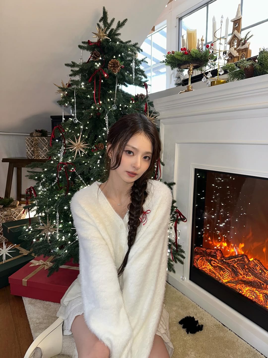 Photo by 이나경 on December 14, 2025. May be an image of one or more people, makeup, sleepwear, christmas tree, Christmas stocking, sweater, bath robe, robe, fireplace and hearth.