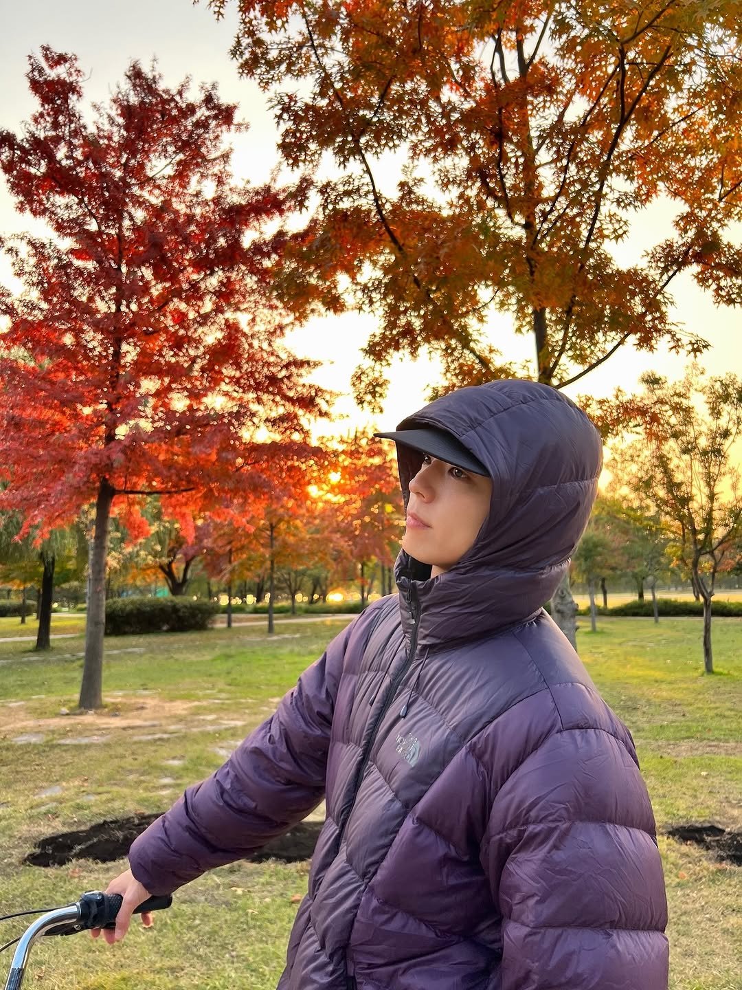 Photo shared by 박보검 PARK BO GUM on November 02, 2025 tagging @thenorthface_kr. May be an image of bicycle, scooter, parka, park and text.