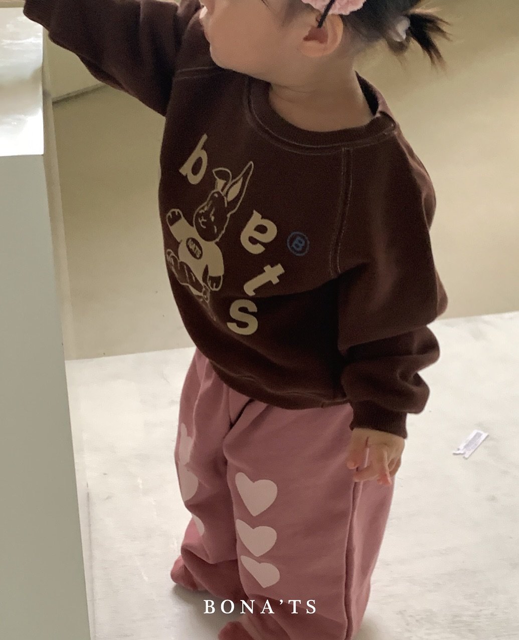 Photo by 보나츠 on September 24, 2025. May be an image of 1 person, sweatsuit, bow, sweatpants, baby shoes, sweatshirt and text that says 'BONA'TS TS'.