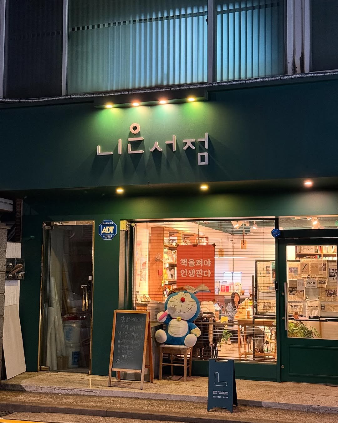 Photo shared by 니은서점 on May 29, 2025 tagging @nhomyungwoo, @txty_is_text, and @yeosilji_writer2. May be an image of display case, signboard and night.