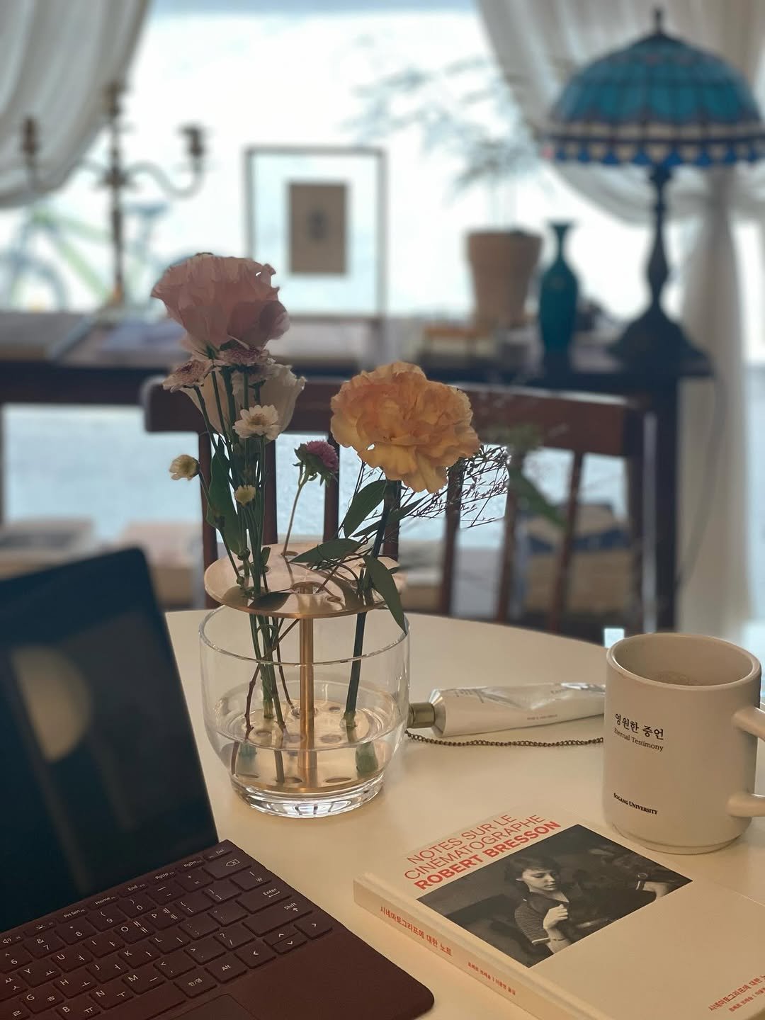 Photo by 책 의 기 분 on December 31, 2025. May be an image of coffee cup, bureau, desk, flower arrangement, beaker, prairie gentian, globe amaranth, carnation, office and text.