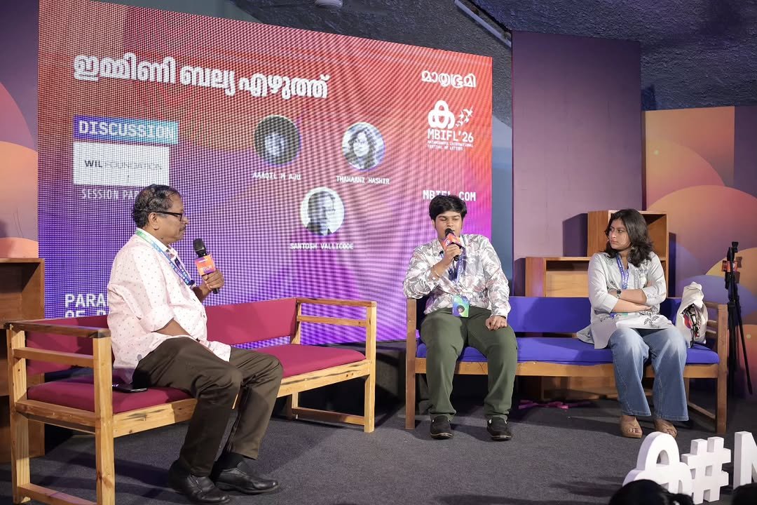 Photo shared by Booksthakam on February 03, 2026 tagging @ajusadasivan. May be an image of one or more people, television, microphone, newsroom and text that says 'ഇമ്മിണിബല്യഎഴുത്ത് ഇമ്മിണി ตยา എഴുത്ത് DISCUSSTONE DISCUS WIL F1510種 മാതൃഭൂമി ക. MBIFL'26 SEY 出 MBIFL '26 THANABNZ HASHER NOTECOM NOTEI coM SANTOSHE VALETCODE PARA PARAL 养特前 A#I'.