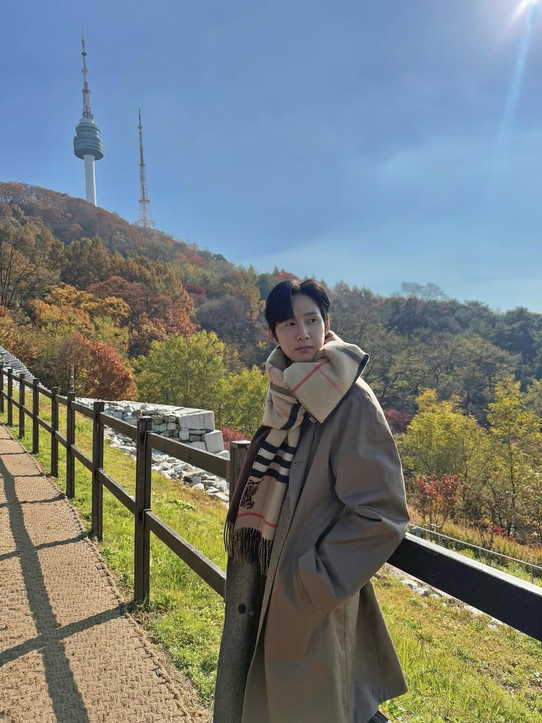 Photo shared by 박스아범 박성훈 on November 20, 2025 tagging @burberry. May be an image of duffle coat, overcoat, parka, outdoors and tower.