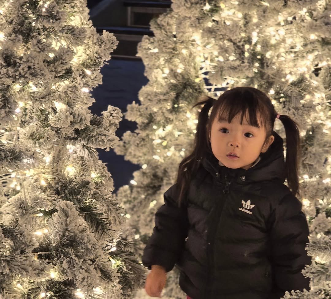 Photo by 루나 on December 25, 2025. May be an image of baby, christmas tree, duffle coat, tinsel and text.
