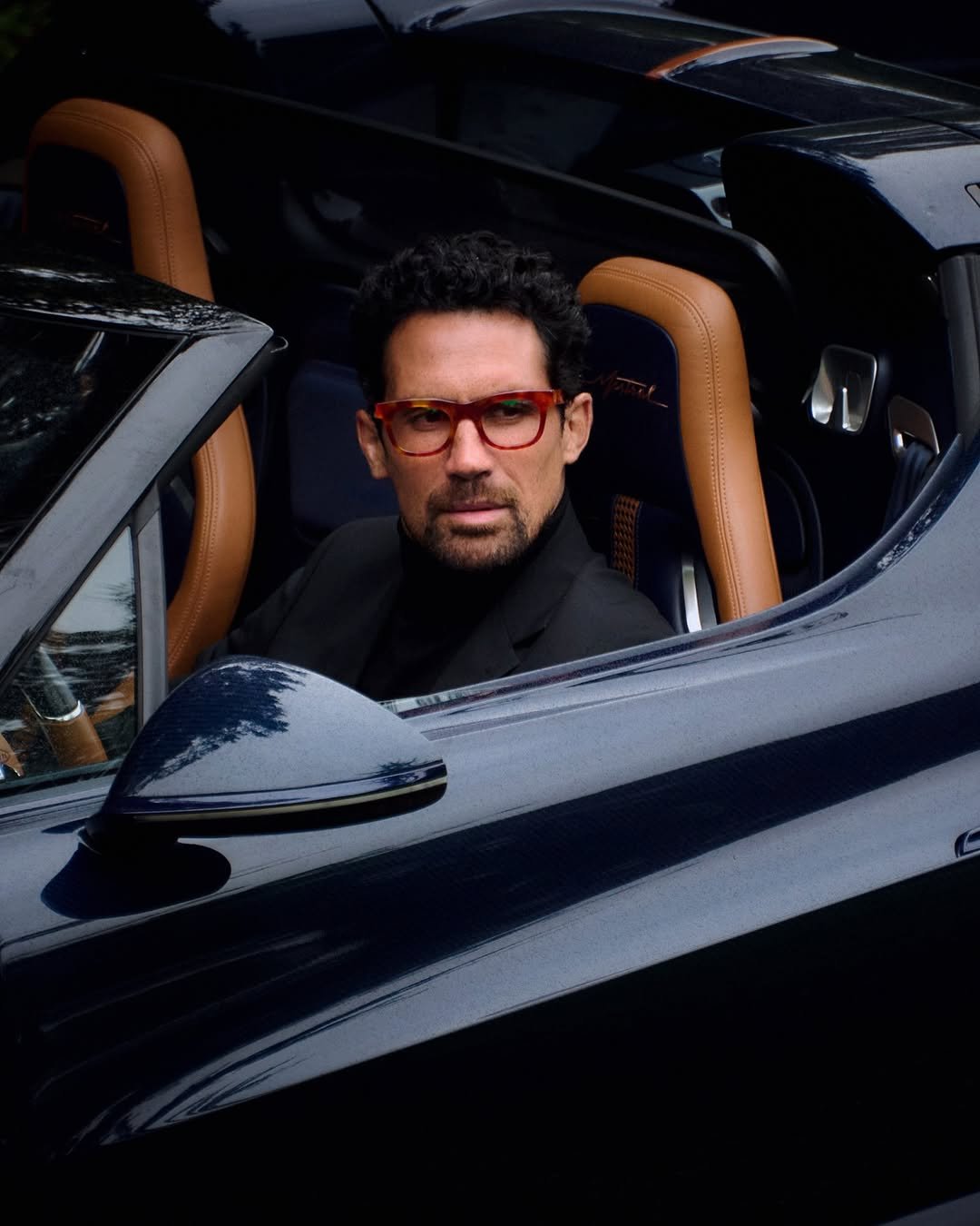 Photo shared by BUGATTI on September 26, 2025 tagging @bugatti_newsroom, and @bugattieyewear. May be an image of 1 person, sunglasses, roadster and text.