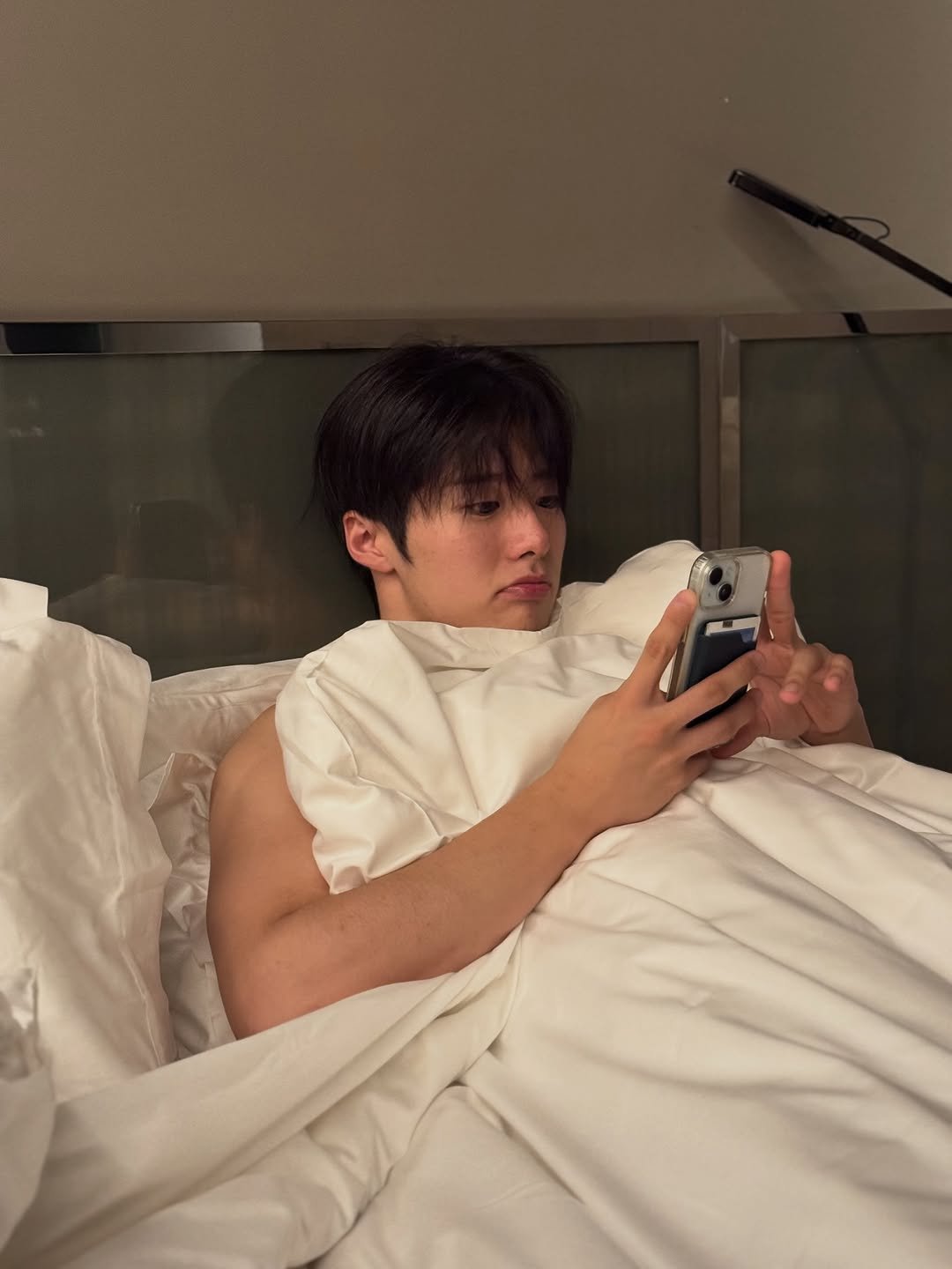 Photo by 조잽미 on October 05, 2025. May be an image of 1 person, phone, sleepwear, bed, bath robe, bedroom and text.