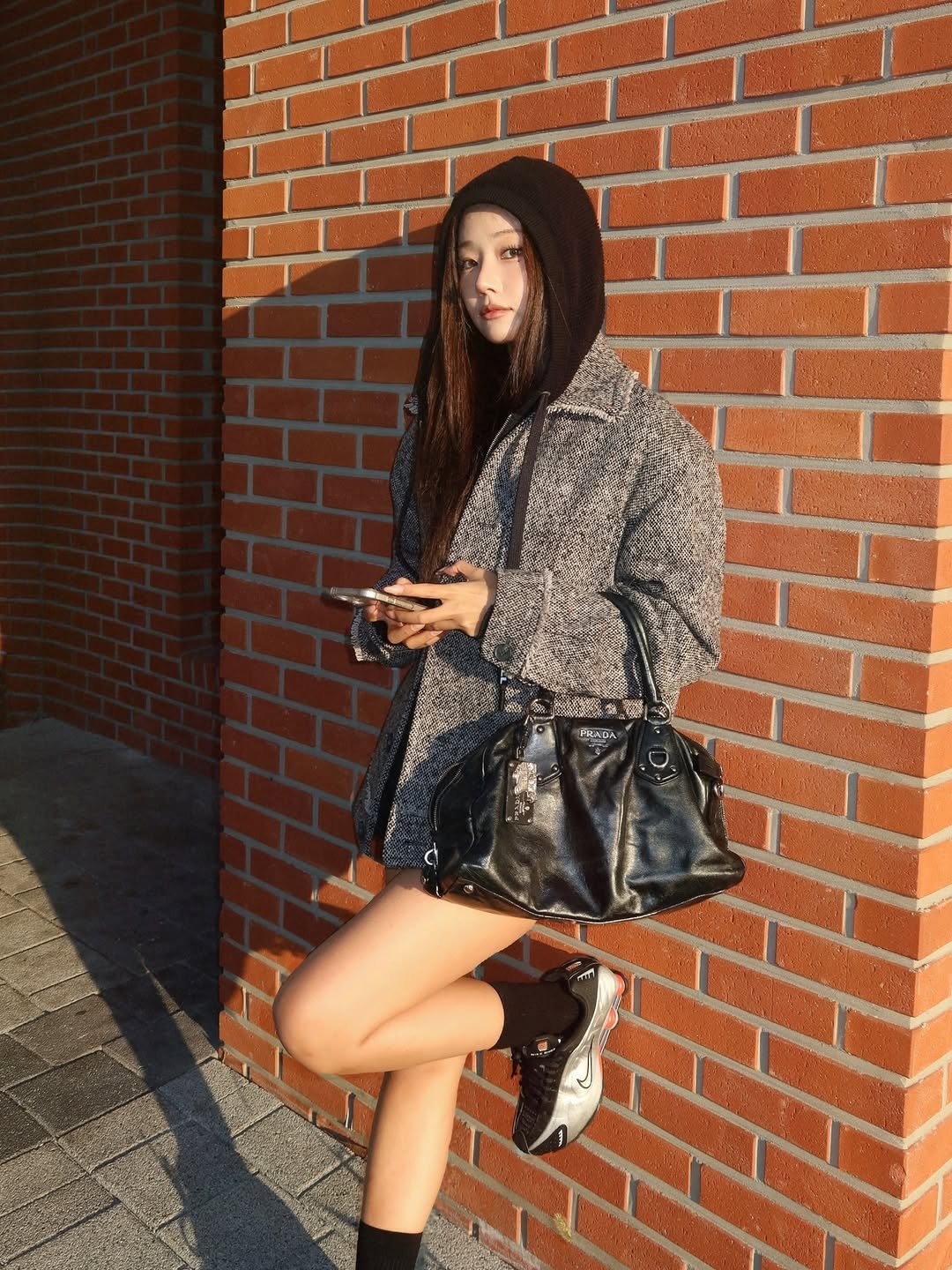 Photo shared by 배지연 on December 02, 2025 tagging @by_eccentric. May be an image of duffle coat, fur coat, purse, fishnet stockings, miniskirt, parka, brick wall and text.