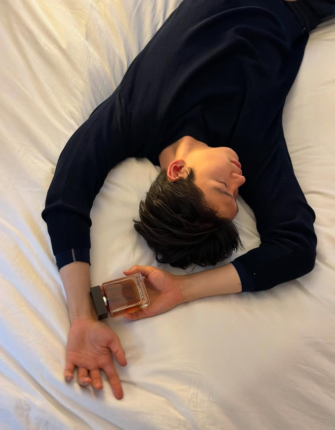 Photo shared by 임지노 on February 01, 2026 tagging @dolcegabbana_beauty. May be an image of sleeping, fragrance, flask, whiskey, bedroom and text.