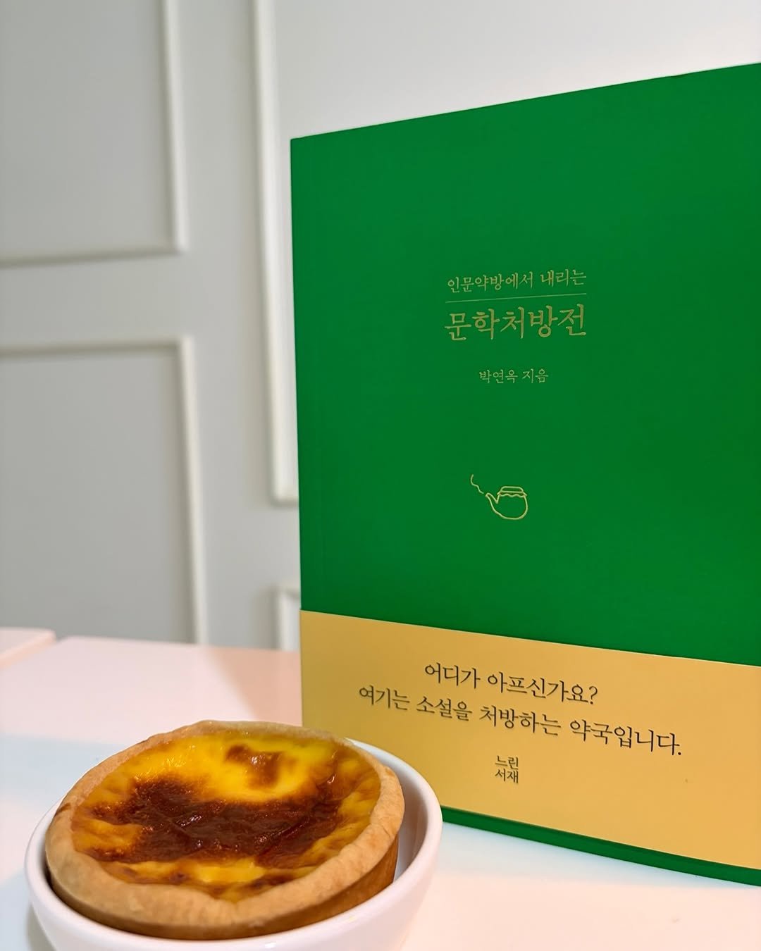 Photo by 느린서재 출판사 on February 17, 2026. May be an image of souffle, tart, cheesecake, pie and text that says '인문약방에서내리는 내리는 인문약방에서 문학처방전 박연옥 박연옥지음 지음 어디가 아프신가요? 여기는 소설을 처방하는 약국입니다. 채채'.