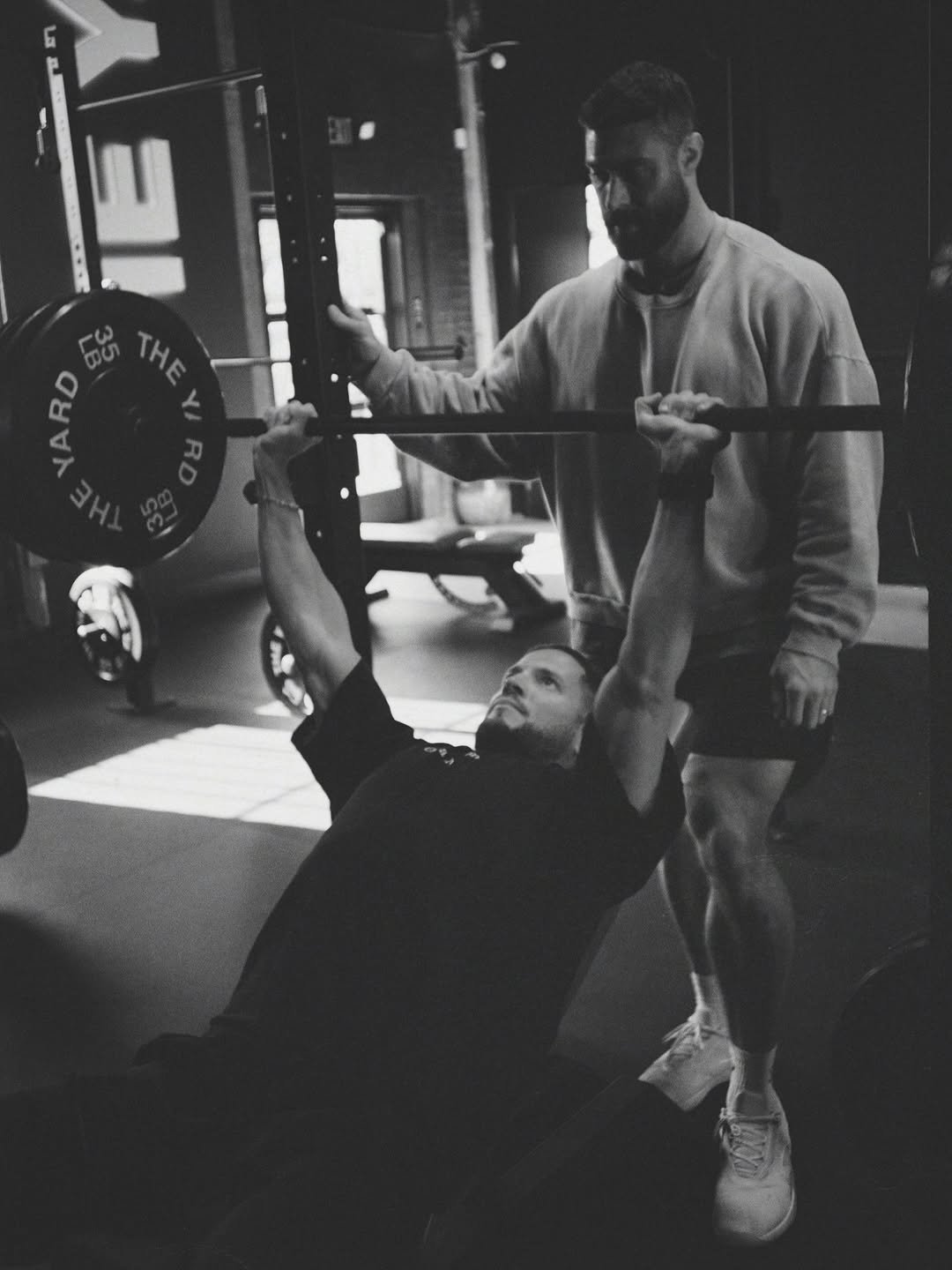 Photo shared by Chris Bumstead on December 17, 2025 tagging @georgeheaton, @diegogarciavisuals, and @theyard_gym. May be a black-and-white image of one or more people, biceps, people bodybuilding, dumbbell, bench, barbell and text.