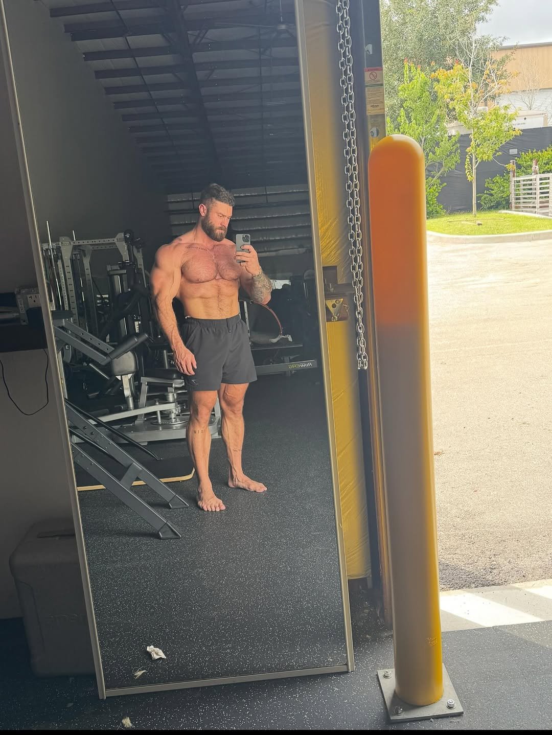 Photo shared by Chris Bumstead on November 16, 2025 tagging @gymshark. May be an image of one or more people, biceps, people bodybuilding, rearview mirror and text.