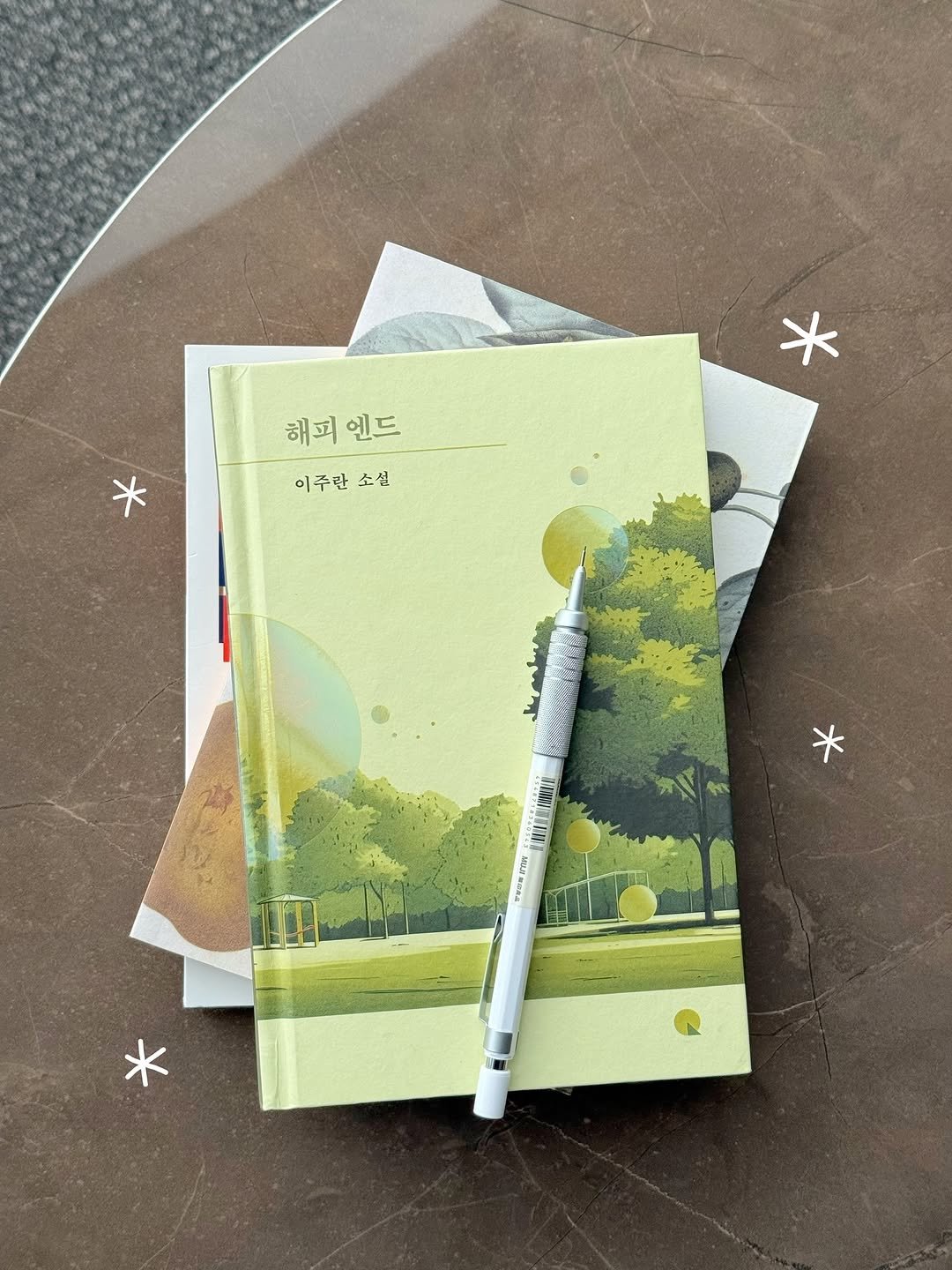 Photo shared by 글린ㅣ글쓰는 ‘린’✍🏻 on November 12, 2025 tagging @changbi_insta, and @high1_resort. May be an illustration of diary, book, pen and text that says '해피 해피엔드 엔드 이주란소실 이주란 소설 * WESATIN'.