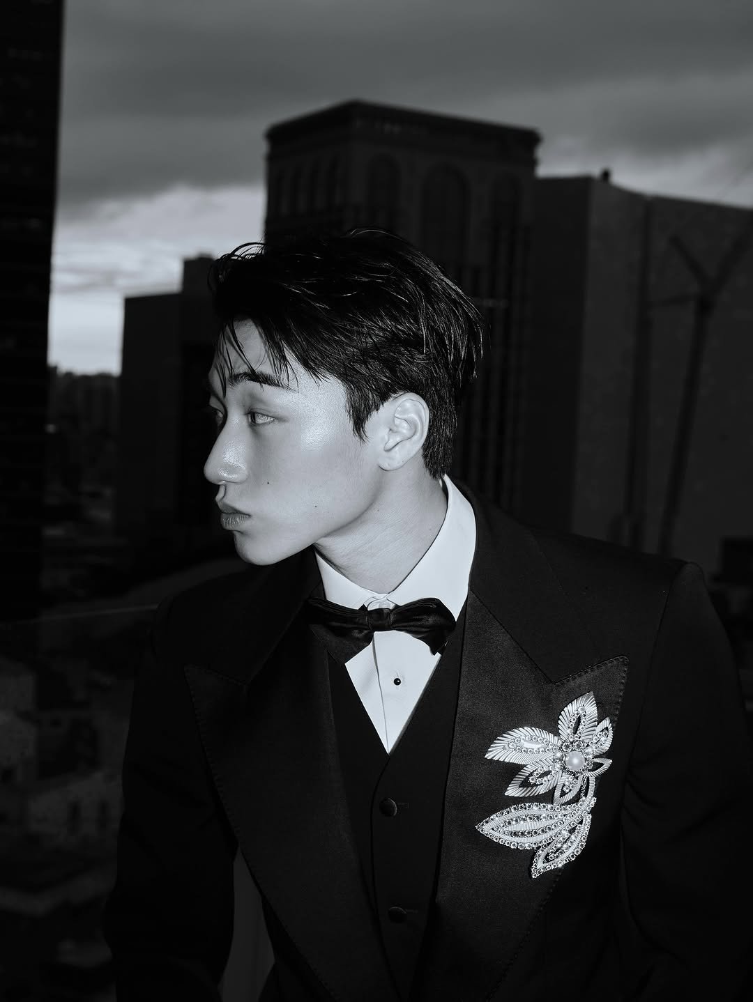 Photo shared by 산 (SAN) on October 15, 2025 tagging @dolcegabbana. May be a black-and-white image of suit, dinner jacket, blazer, bolo tie and bowtie.