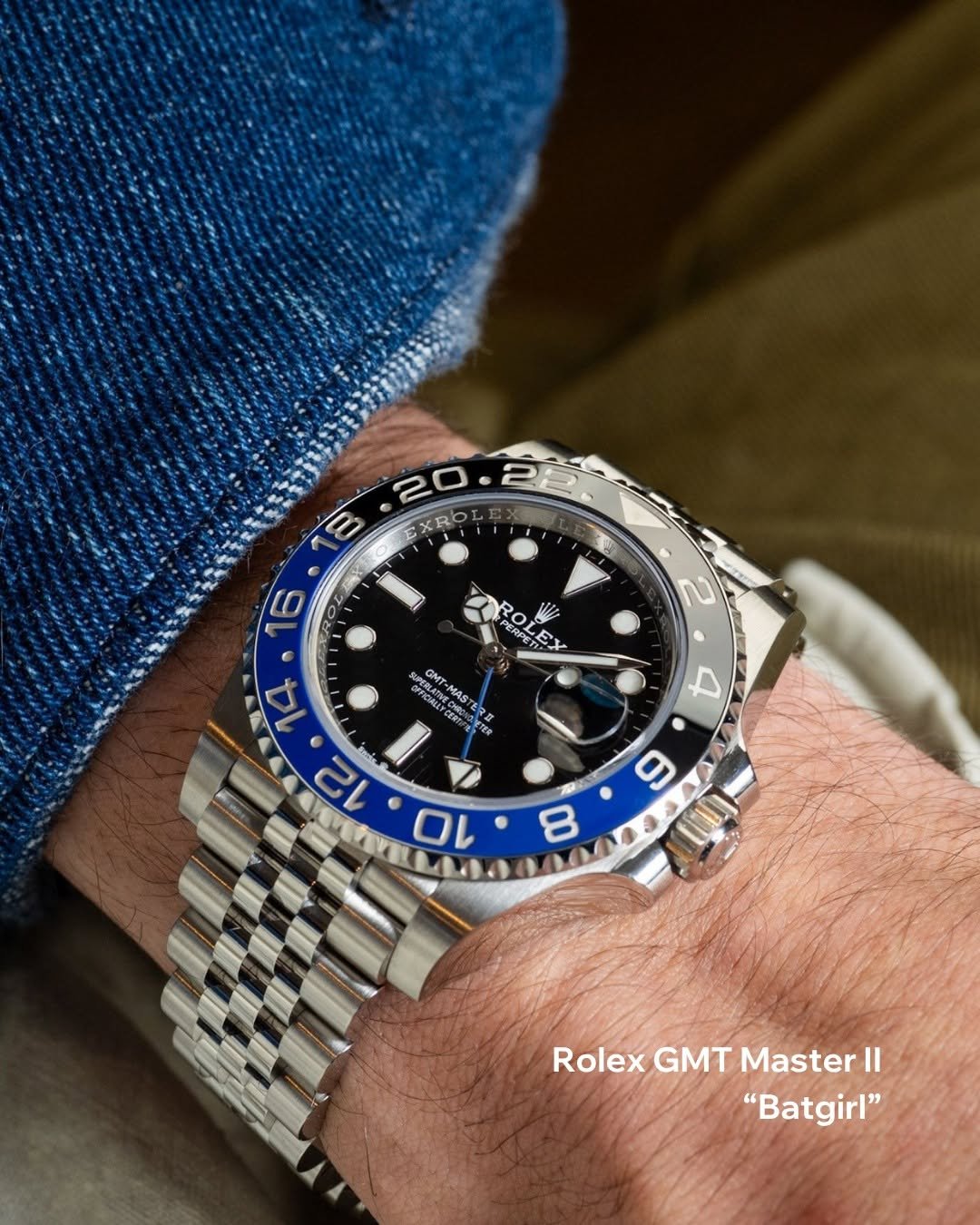chrono24 watches image watch luxurywatch preowned
A Rolex GMT Master II "Batgirl" watch is on a person's wrist. The watch features a black and blue bezel with a stainless steel Jubilee bracelet. The dial is black with large, luminous hour markers and hands. There is also a date magnification window. The person is wearing a blue textured fabric, possibly a sweater, with the watch prominently displayed.