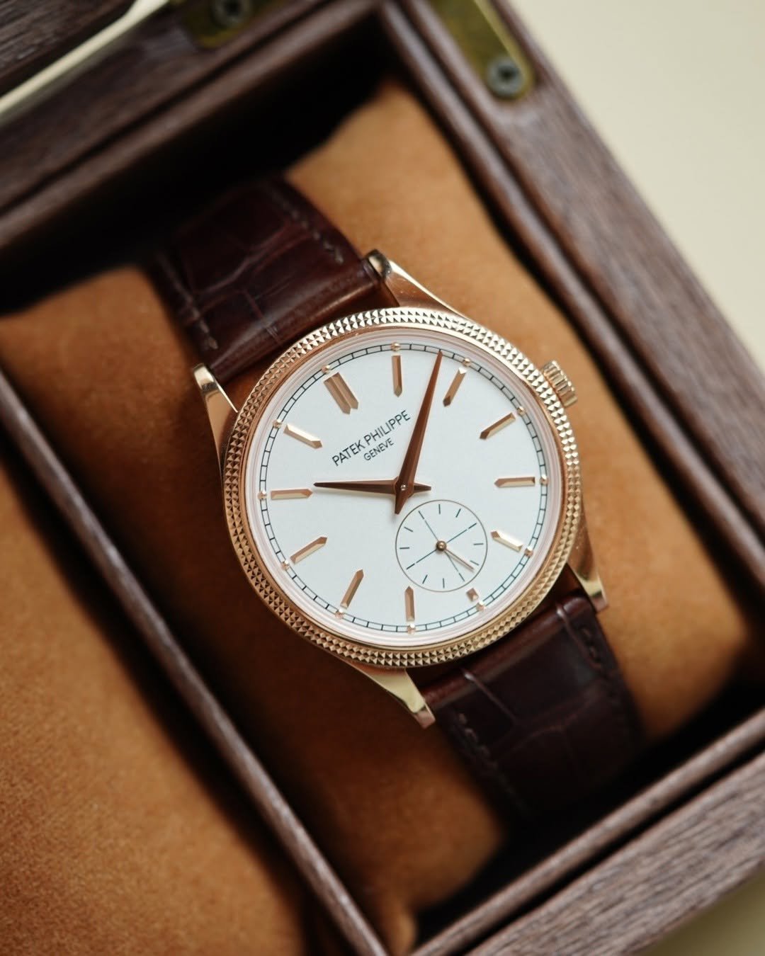 chrono24 watches image watch luxurywatch preowned
A luxury wristwatch with a white face and rose gold case, featuring brown leather straps, is displayed inside a wooden box lined with soft tan fabric. The watch has a minimalistic design with slender gold hour markers and hands, and a small subdial above the 6 o'clock position.