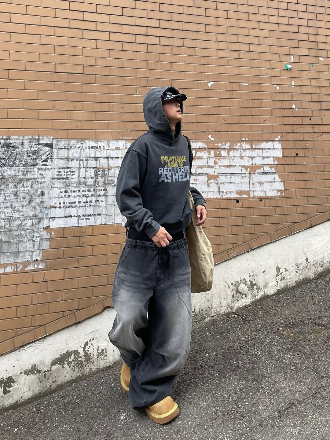 Photo shared by 정인 on April 06, 2026 tagging @glamour_ism. May be an image of standing, parka, street, brick wall and text.