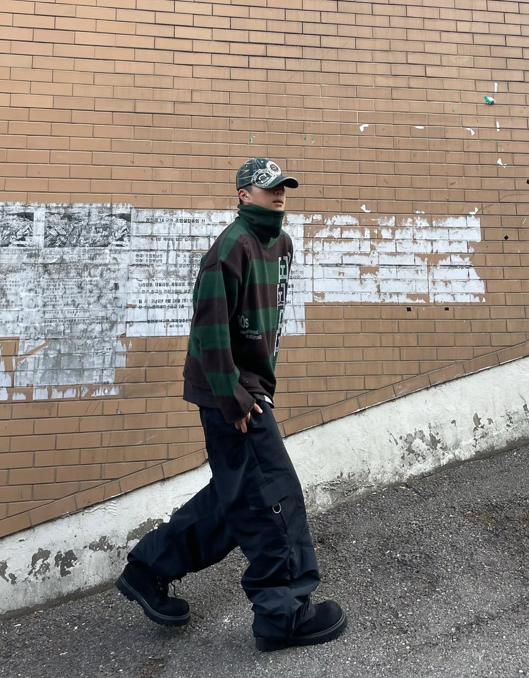 Photo shared by 정인 on April 12, 2026 tagging @massnoun, and @massnoun_archive. May be an image of standing, face mask, outerwear, flannel, kilt, brick wall and text.