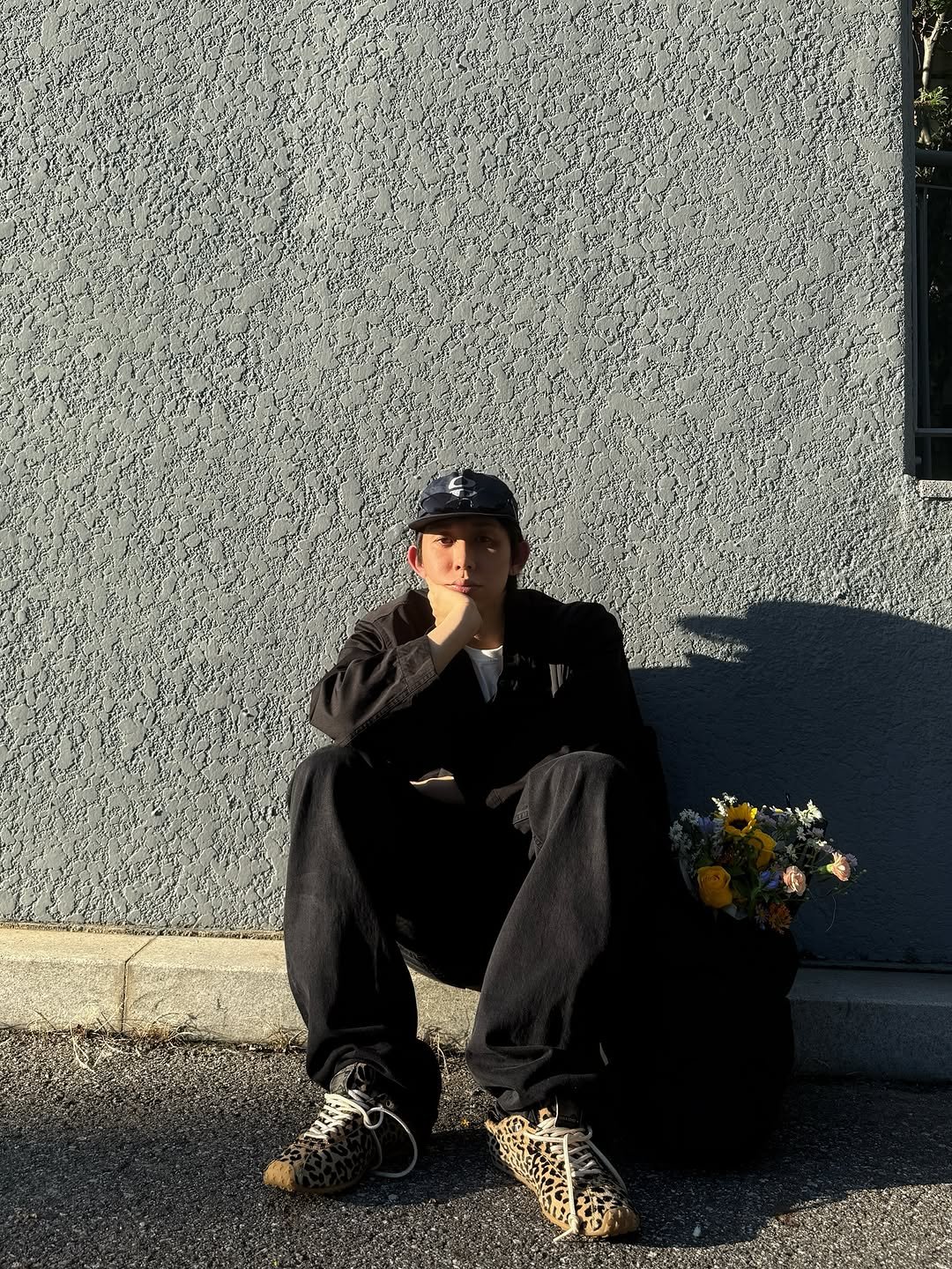Photo shared by CODE KUNST on September 15, 2025 tagging @goldengoose. May be an image of one or more people, people smoking, cigarette, grave stone, bowler hat, curb and text.