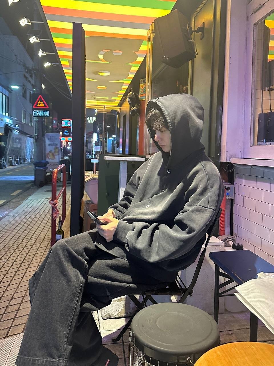 Photo by 채형원 hyungwon on November 03, 2025. May be an image of smoking, duffle coat, overcoat, umbrella, cigarette, parka, bath robe, street and text.