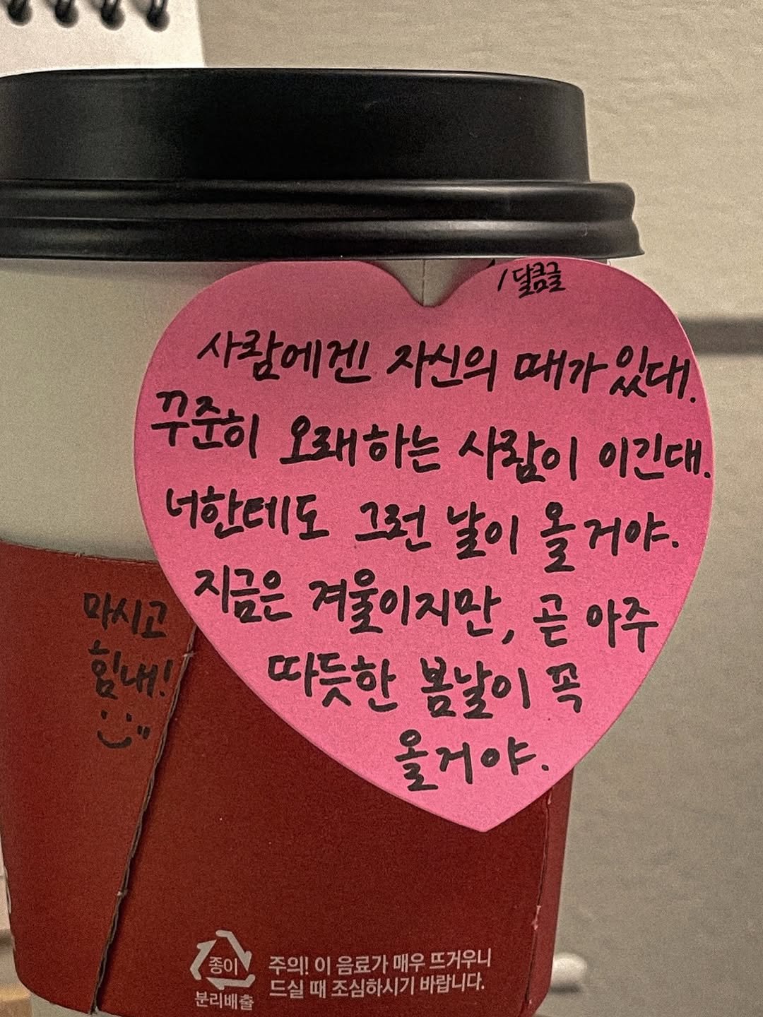 Photo by 달큼글, 예원 on December 17, 2025. May be an image of drink, heart and text that says '/달콤크 사람에겐 자선의 매가 때가있대. 있대!. 꾸준히 오래하는 사람이 이긴대. 너한데도 그런 그런날이 날이 올거야. 지금은 겨울이지만, 아주 따듯한 봄날이 弓 올거야, ো 종이 주의! 이 음료가 매우 뜨거우니 분리배출 드실 때 조심하시기바랍니다. 조심하시기 바랍니다.'.