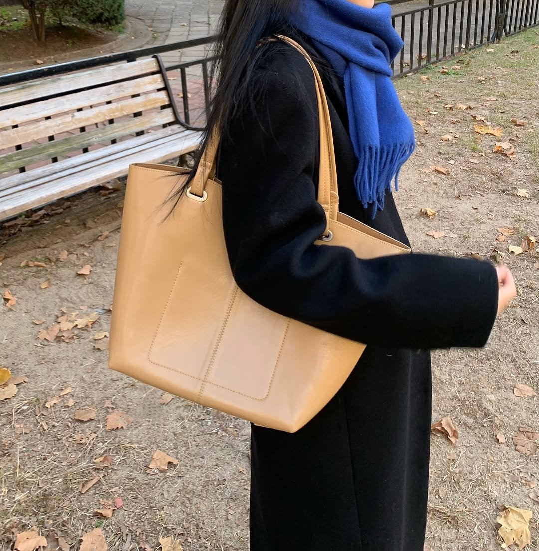 Photo shared by 오브던🌹 on November 12, 2025 tagging @apoa._official. May be an image of saddle-stitched leather, duffle coat, scarf, purse, briefcase and text.
