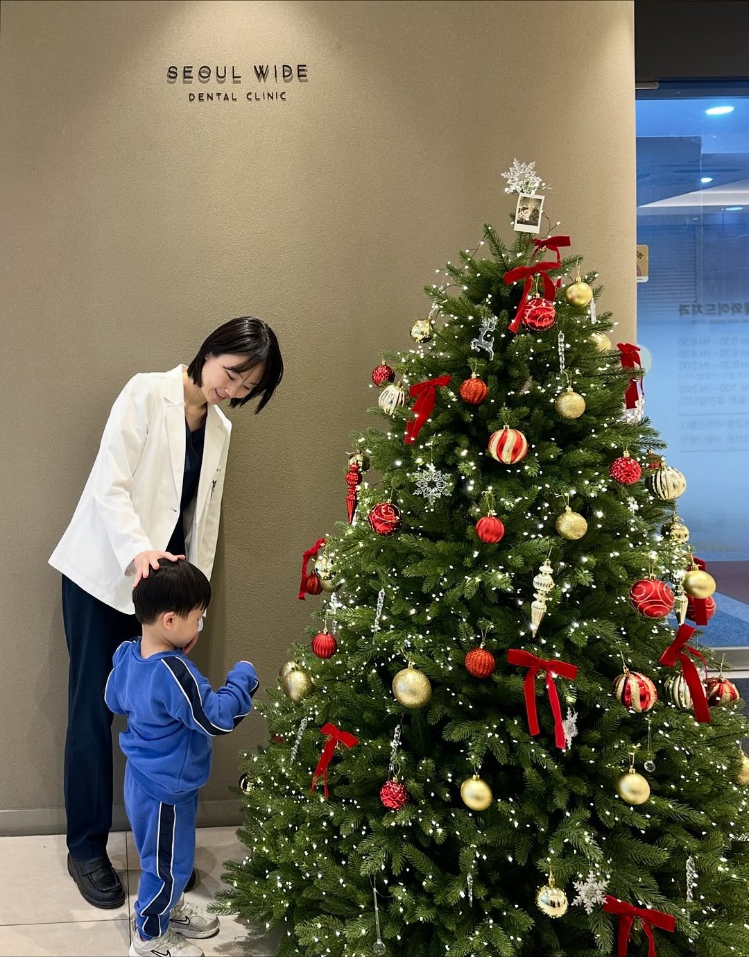 Photo by 권수진 | 치과의사 | 치아교정, 인비절라인 | 연년생 엄마 on November 14, 2025. May be an image of child, hair, duffle coat, christmas tree, tinsel and text that says 'SEOULWIDE SEOUL WIDE D DENTALCLINIC DENTAL CLINIC'.