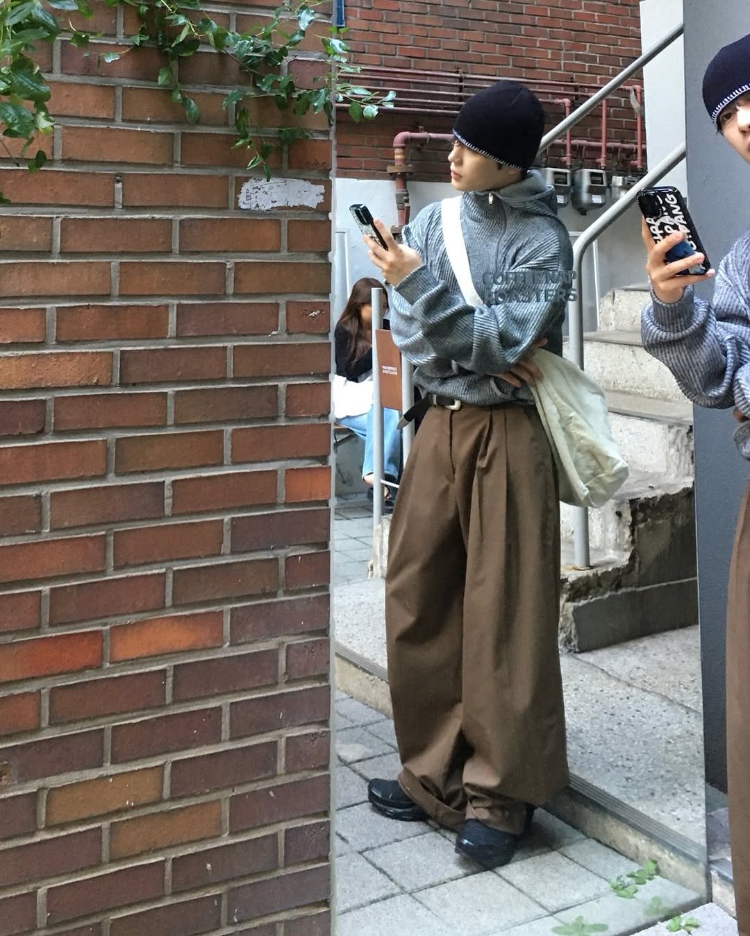 Photo by 도형, 디멘트 DMENT on September 30, 2025. May be an image of 2 people, phone, duffle coat, headscarf, street, brick wall and text.