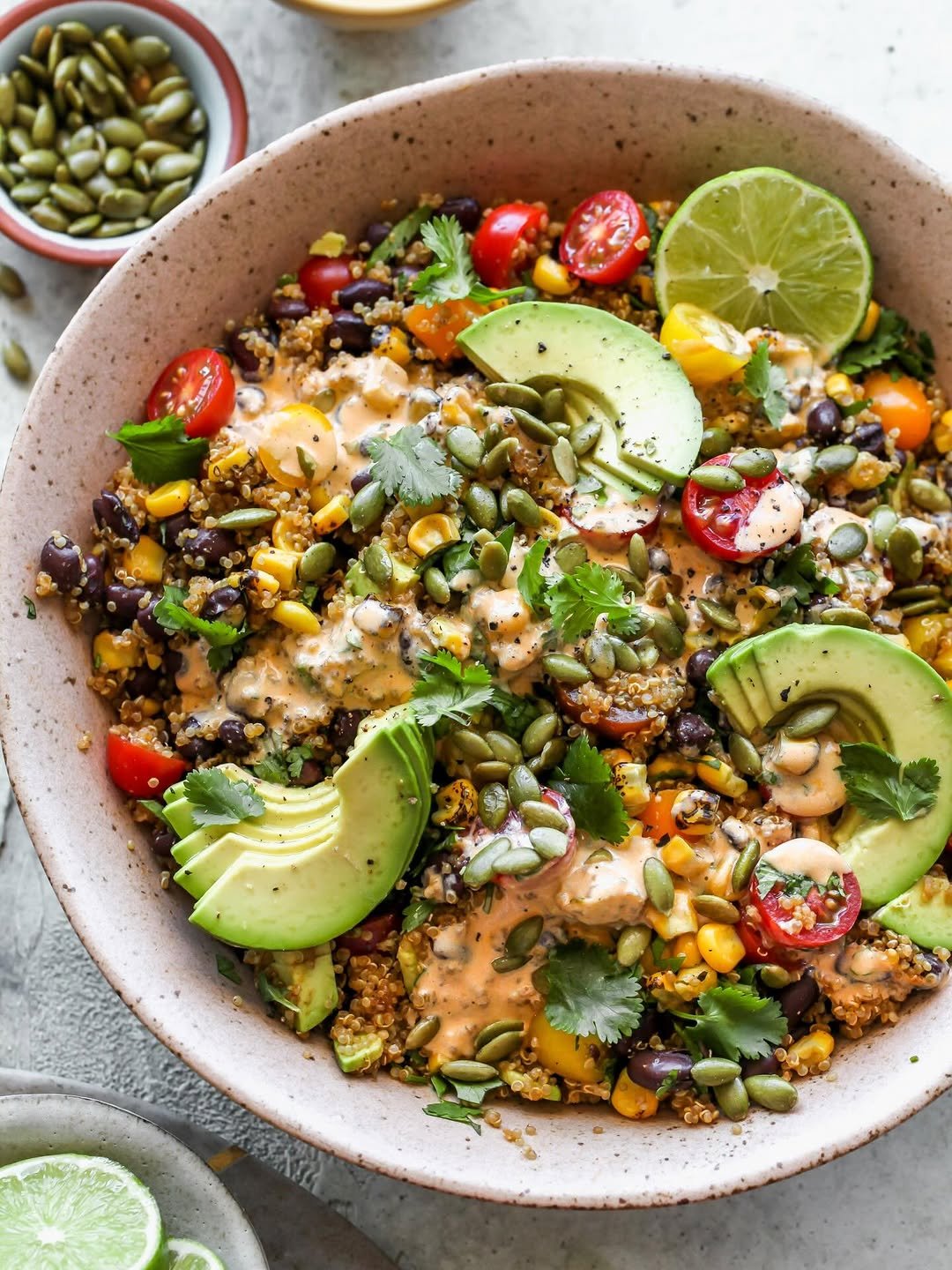Quinoa Southwest salad topped with creamy chipotle dressing and avocado slices styled in a large pink serving bowl.