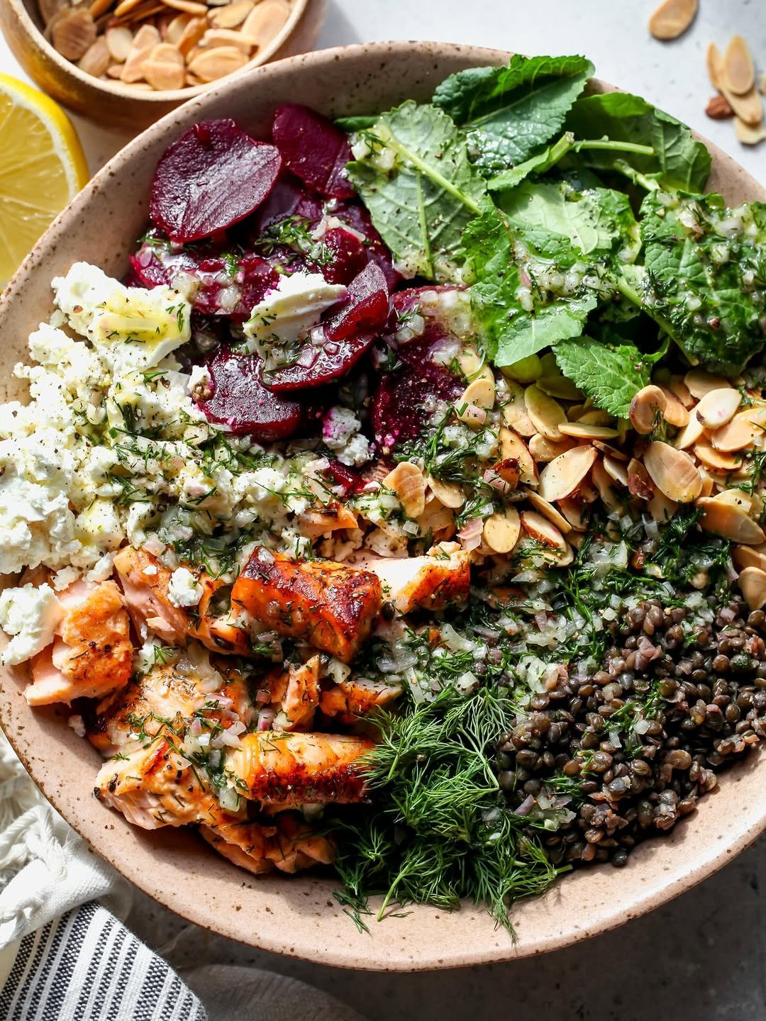 Mediterranean salmon and lentil salad, styled in a large serving bowl drizzled with dressing and feta cheese.