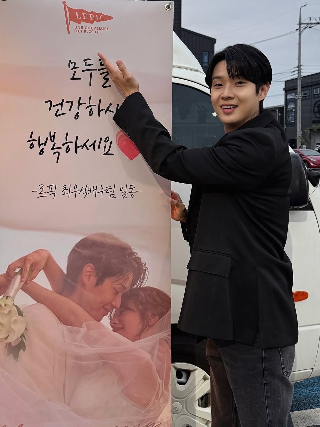 Photo by CHOIWOOSHIK on October 09, 2025. May be an image of 2 people, poster and text that says 'LEPIC NE CHEVELURE QUI FLOTTE 모두를 건강하시 행복하세요 -르픽 최우식배우팀 r2 일동-'.