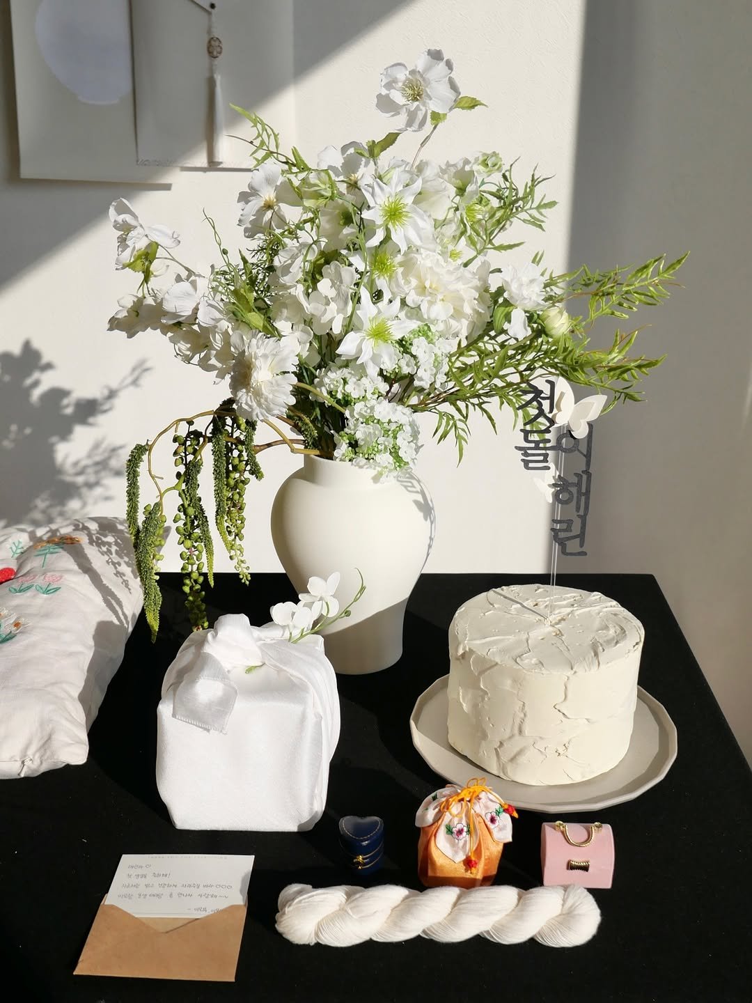 Photo shared by 도둥이네 on March 23, 2026 tagging @hiona_day. May be an image of wedding cake, placemat, flower arrangement, tablecloth, prairie gentian, amaranth, baby's-breath and text.