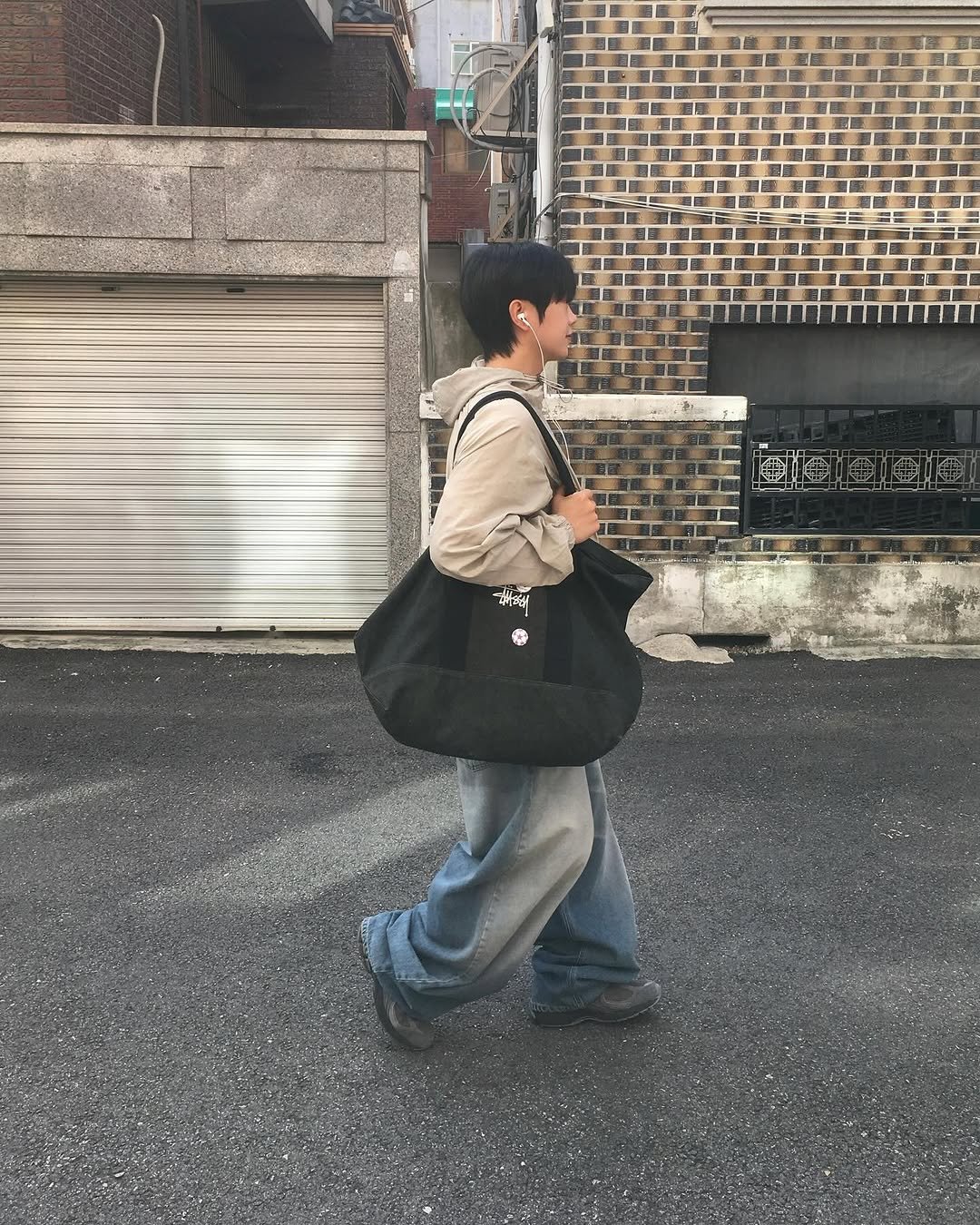 Photo shared by 동현 / 투븐 TOVN on September 19, 2025 tagging @tovn_official. May be an image of 1 person, tool bag, sling, grocery bag, street and text.